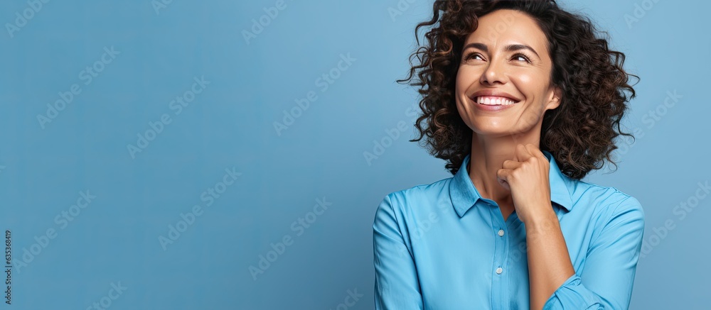 A Brazilian woman in her mid life presenting an idea with a smile while standing alone on a blue background