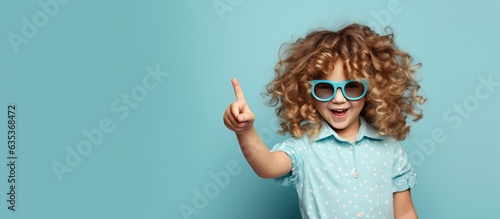 Funny preteen girl with serious expression promotes children s product on blue background photo
