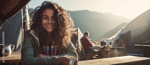 Smiling Latin woman enjoying breakfast in the mountain camp on a sunny morning holding a hot drink