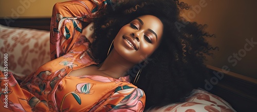 Happy African model wearing an animal print dress lying down while smiling and looking at the camera Indoor portrait with copy space