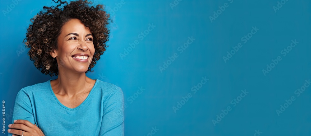 A Brazilian woman in her mid life presenting an idea with a smile while standing alone on a blue background