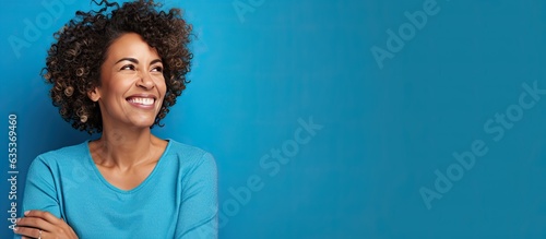 Obraz na płótnie A Brazilian woman in her mid life presenting an idea with a smile while standing alone on a blue background w salonie
