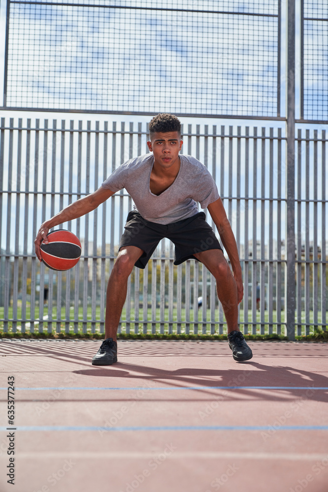 Black man playing basketball on sports ground