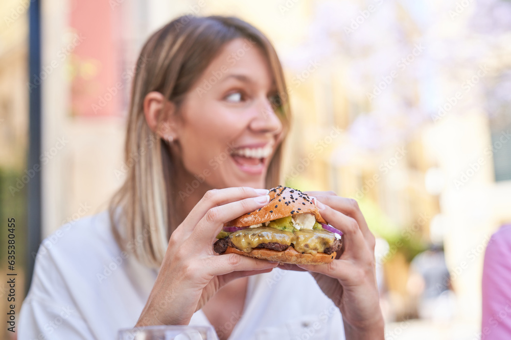 Happy woman eating appetizing hamburger Happy woman eating appetizing hamburger