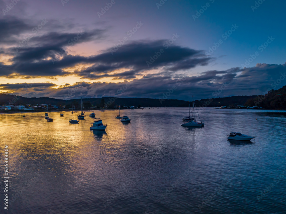 Aerial sunrise waterscape with boats and scattered rain clouds