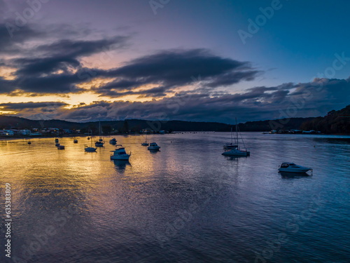 Aerial sunrise waterscape with boats and scattered rain clouds