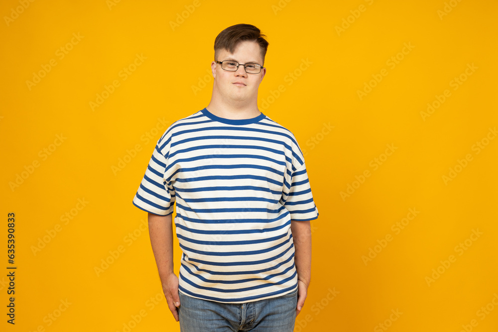 Smiling young man with cerebral palsy in glasses in a striped t-shirt on a yellow background. World Genetic Diseases Day concept Smiling young man with cerebral palsy in glasses in a striped t-shirt on a yellow background. World Genetic Diseases Day concept