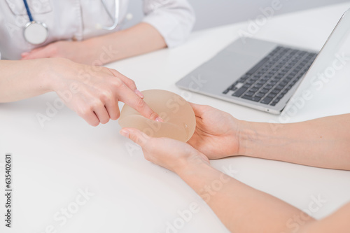 Caucasian woman and plastic surgeon touching and choosing breast implants. 