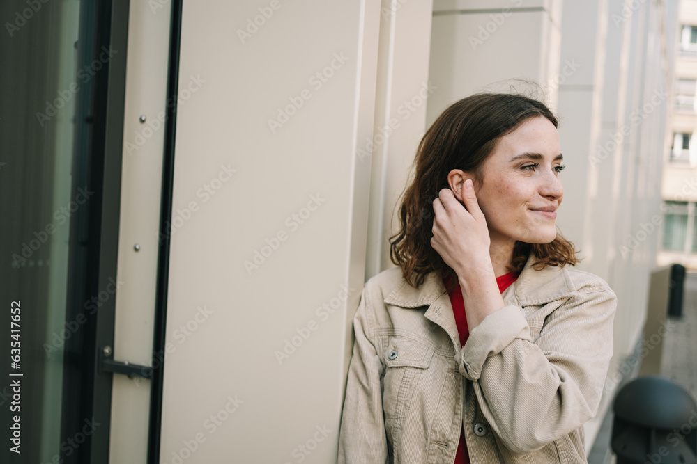 Young Woman Leaning on Modern Facade with a Smiling Glance Young Woman Leaning on Modern Facade with a Smiling Glance
