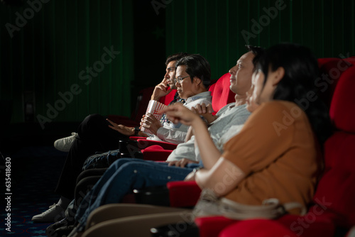 Asian mother and daughter watching movie in cinema. Family time concept.