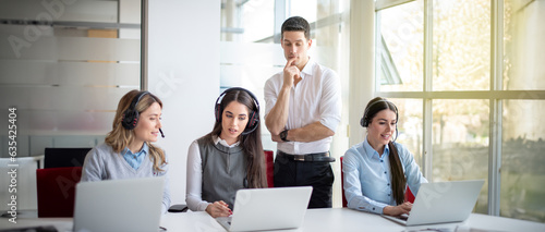 Foto Business women discussing potential problem on laptop with assistance of their male supervisor, solving problem together in office