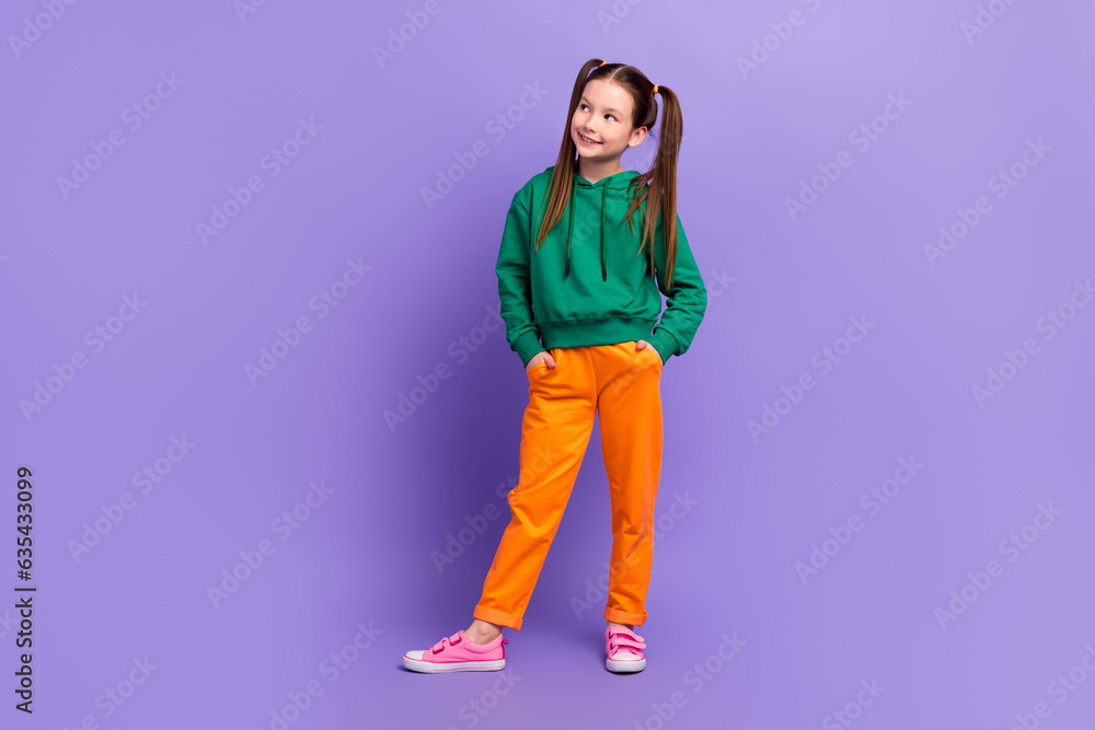 Full length portrait of funny little girl look empty space wear sports clothes sweatshirt pants isolated purple color background Full length portrait of funny little girl look empty space wear sports clothes sweatshirt pants isolated purple color background