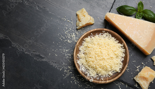 Whole and grated parmesan cheese on black table, flat lay. Space for text photo