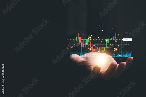 Delving into the intricacies of the stock market, a trader or investor focuses on their palm-held device, observing a candlestick chart and employing intelligent strategies for successful trading.