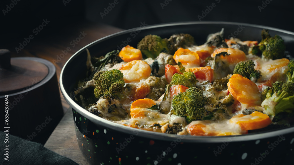 Gratin with broccoli, carrots and cheese baked in the oven on a dark wooden table