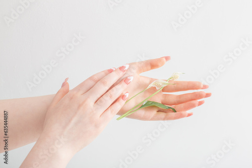 female hands with beautiful long nails with  flowers on white background