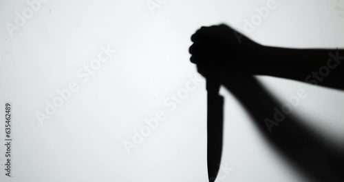 The shadow of a murderer kills his victim with a knife at night.
 photo