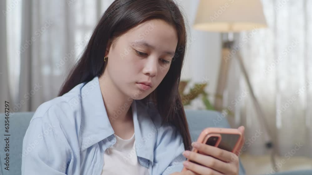 Close Up Of Asian Teen Girl Recording Voice Message On Smartphone While Sitting On Sofa In The Living Room At Home
