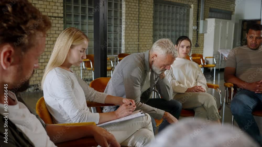 Senior man wiping away tears in group counseling seance Senior man wiping away tears in group counseling seance