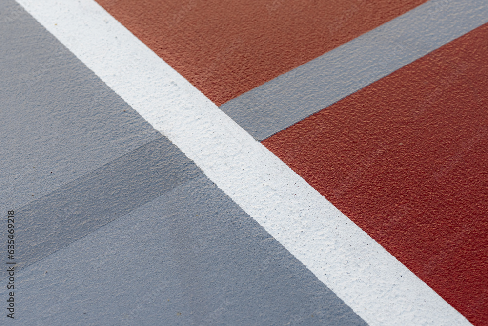 Fototapeta premium Wet red tennis court with white lines combined with gray pickleball lines