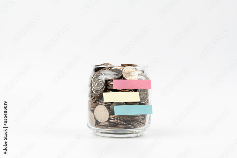 Many coins in a bottle with notepad isolated on white background , saving money for future , loan investment concept Many coins in a bottle with notepad isolated on white background , saving money for future , loan investment concept