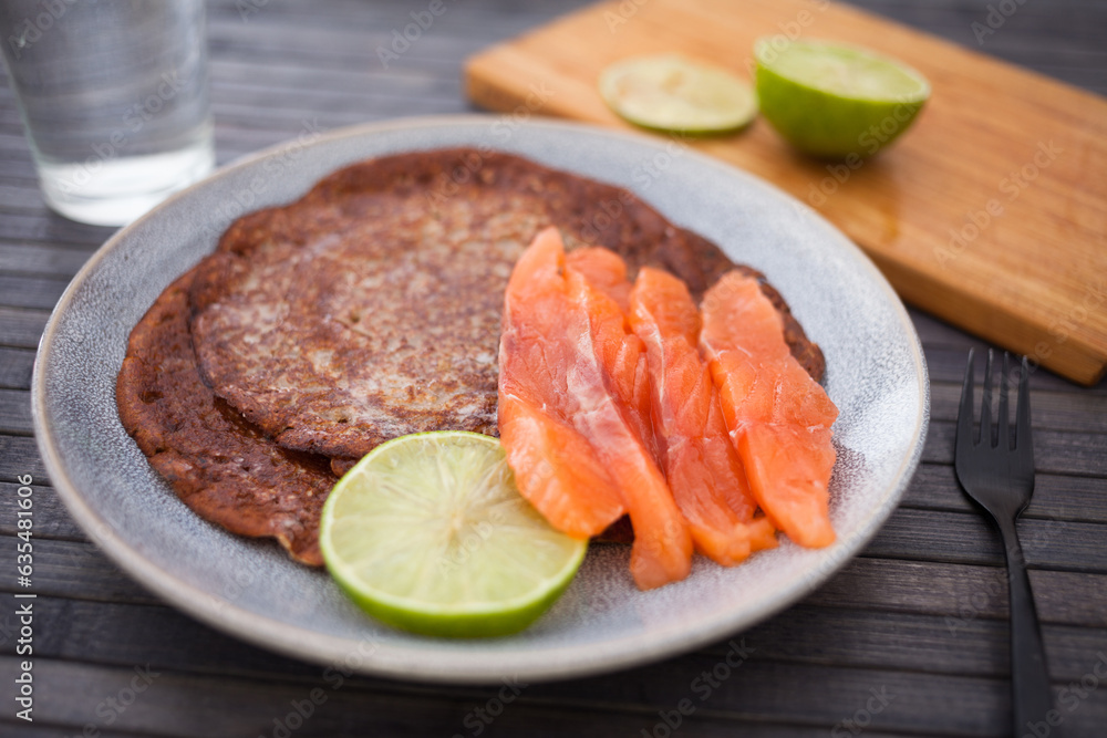 Healthy breakfast of pieces of salted smoked salmon with buckwheat pancakes and lime Healthy breakfast of pieces of salted smoked salmon with buckwheat pancakes and lime