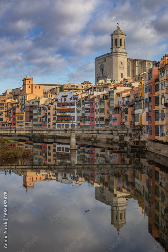 Colorful houses and the cathedral of Girona, Spain, reflected in water, taken from the Eiffel bridge