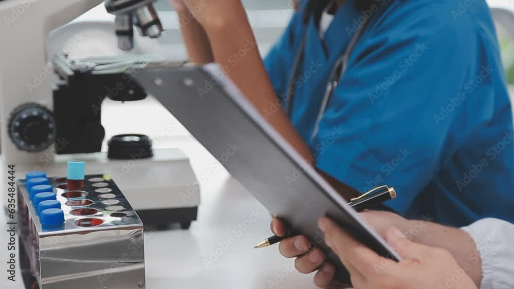 Health care researchers working in life science laboratory. Young female research scientist and senior male supervisor preparing and analyzing microscope slides in research lab.