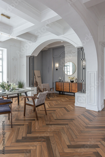 a view of a set dining table in a chic expensive bright interior of a huge living room in a historic mansion with arched arches, columns and white walls decorated with ornaments and stucco.