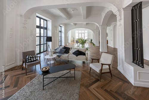 a chic expensive bright interior of a huge living room in a historic mansion with arched arches, columns and white walls decorated with ornaments and stucco.