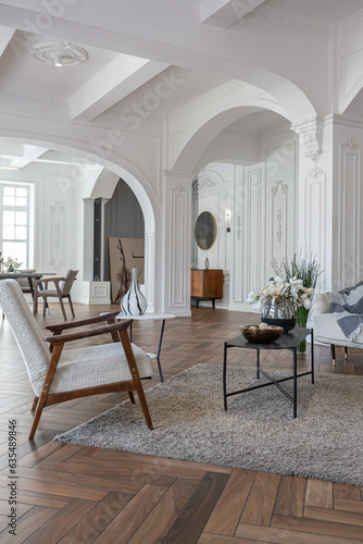 a chic expensive bright interior of a huge living room in a historic mansion with arched arches, columns and white walls decorated with ornaments and stucco. © 4595886