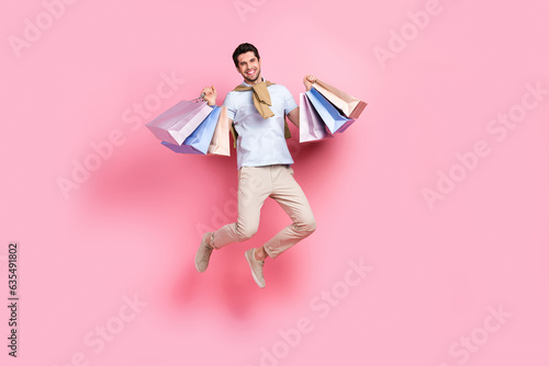 Full body photo of young jumping carefree man need more expensive clothes gucci brand brand packages isolated on pink color background