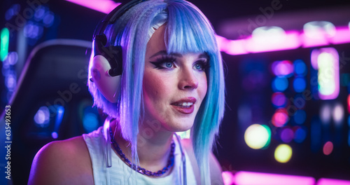 Close Up Portrait of a Beautiful Young Female Wearing Headphones  Talking with Friends Online on a Computer. Popular Cosplay Streamer Chatting with Internet Fans. Gamer Girl Playing Video Games