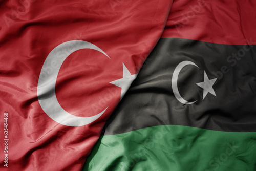 big waving national colorful flag of turkey and national flag of libya . photo