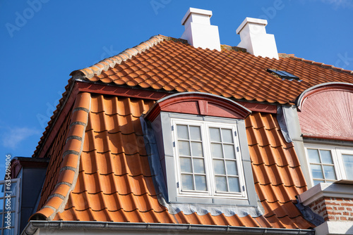 Tiled house roof with chimney and windows.