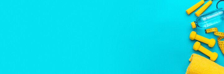 Flat lay photo of fitness equipment over turquoise blue backgound. Top view of yellow street workout objects. Yellow fitness objects on the blue background with some copy space