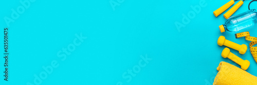 Flat lay photo of fitness equipment over turquoise blue backgound. Top view of yellow street workout objects. Yellow fitness objects on the blue background with some copy space