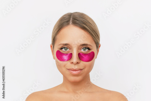 Portrait of young attractive caucasian blonde woman with bright pop pink gel glittering patches on the skin under her eyes isolated on a white background. Skin care, cosmetology. Beauty concept