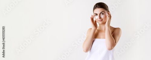Beautiful young brunette woman applying under eye hydrating patches against white studio background. Concept of female beauty, skin care, cosmetology and cosmetics, health, ad © master1305