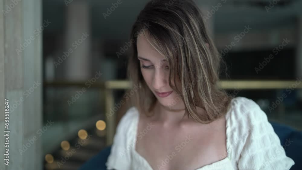 Plano cercano de chica joven chateando por el smartphone sentada en hall de hotel Plano cercano de chica joven chateando por el smartphone sentada en hall de hotel