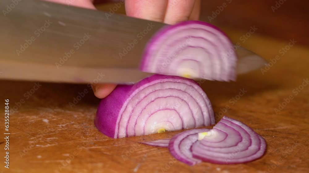 Cutting red onion on wooden cutting board Cutting red onion on wooden cutting board