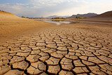Cracked earth with dried up lake in background. Global warming and water scarcity concept.
