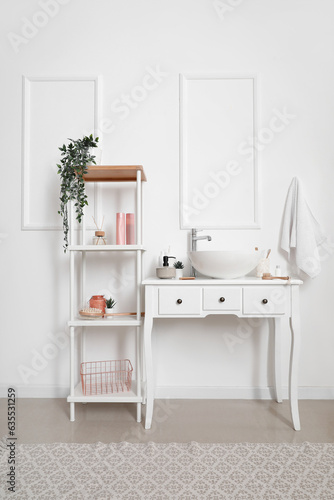 Table with sink bowl and shelving unit in interior of bathroom