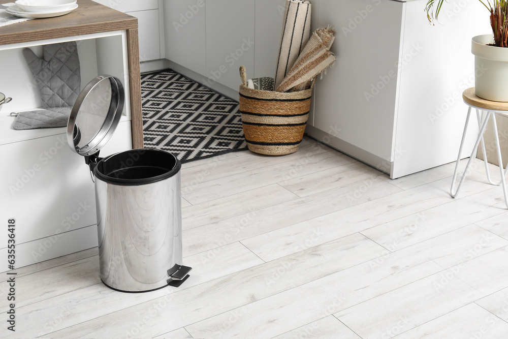Opened metallic trash bin near table in interior of modern kitchen Opened metallic trash bin near table in interior of modern kitchen