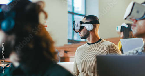 Close up of multiethnic males and female students in VR glasses studying at college and turning heads left and right. Hi-tech study. Mixed-races young people learning technologic ways of education.