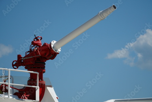 Red and white water cannon on a fireboat to extinguish a fire on the blue sky background