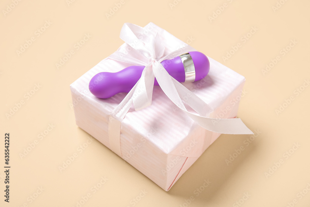 Fototapeta premium Gift box and vibrator on beige background, closeup