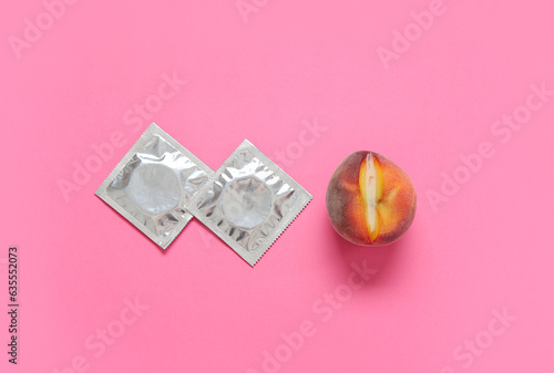Fresh peach and condoms on pink background. Sex education concept