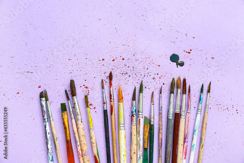 Artist's brushes with paints on lilac background