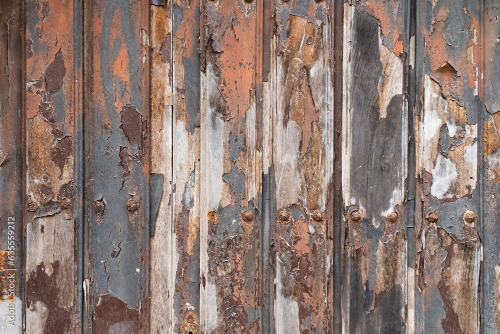 Antique door with vertical wooden slats with lots of texture in orange and grey tones.